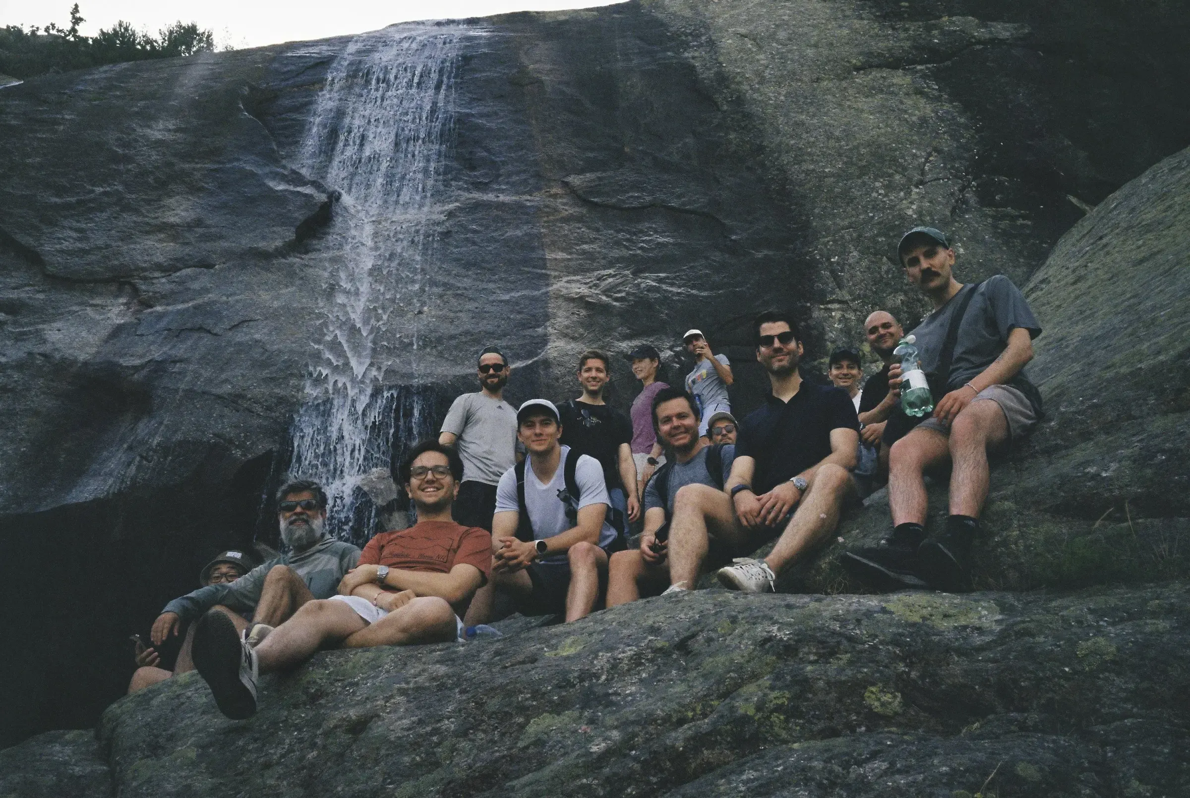 The Causa Prima team on an offsite, sitting on the rocks below a waterfall.