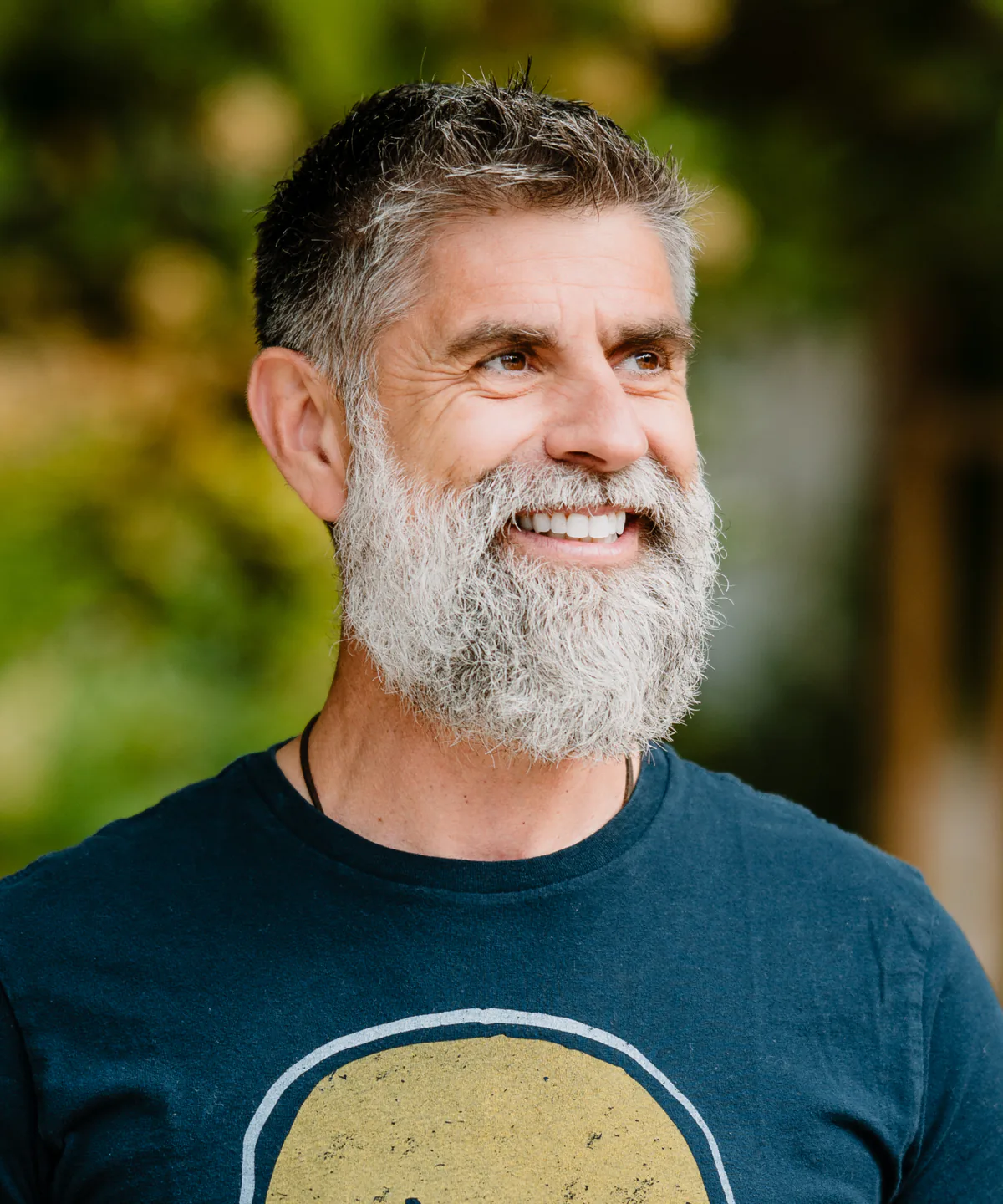 Maex Ament, smiling, in a navy T-shirt, outdoors.